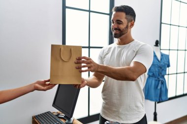 Elbise mağazasında alışveriş çantası tutan genç İspanyol bir müşteri.