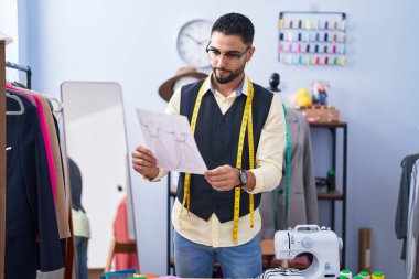 Genç Arap adam giyim fabrikasında elbise tasarımı yapıyor.