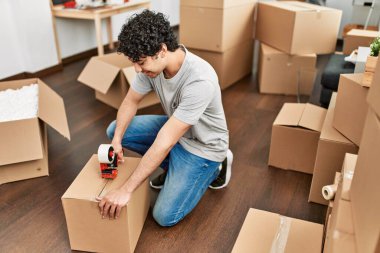 Genç İspanyol adam gülümsüyor yeni evinde mutlu bir paket kutusu var..