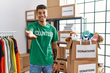 Bağışlarda gönüllü tişört giyen yakışıklı İspanyol genç adam gülümseyerek avuçlarını açıp yardım ve kabullenme teklif ediyor.. 