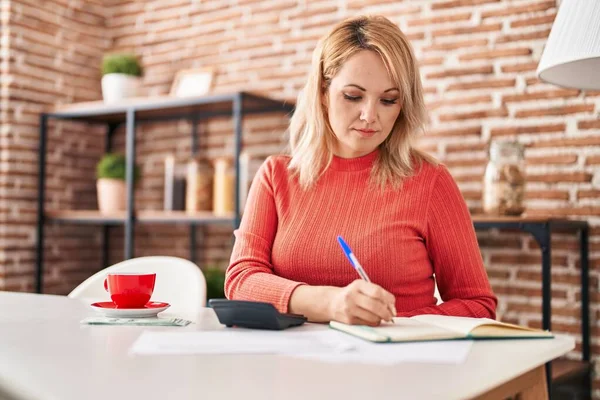 Junge Blonde Frau Sitzt Auf Tisch Und Rechnet Hause — Stockfoto