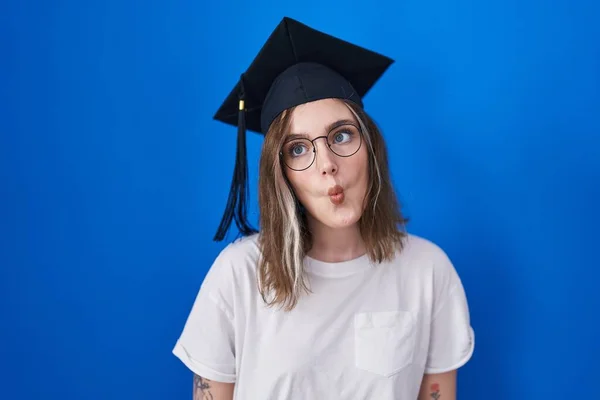 唇で魚の顔を作る卒業キャップを身に着けているブロンドの白人女性 狂気とコミカルなジェスチャー 面白い表現 — ストック写真