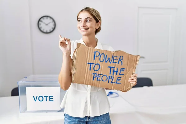 年轻的金发女郎在政治选举中对着人民掌握权力 高高兴兴地微笑着 手指手画脚地指向一边 — 图库照片