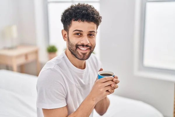若いですArab男飲むカップのコーヒー座っています上のベッドルームで — ストック写真
