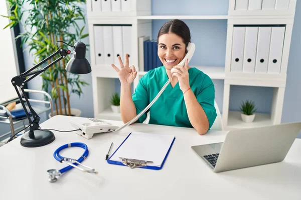 Ung Latinamerikansk Läkare Kvinna Talar Telefon Kliniken Gör Tecken Med — Stockfoto
