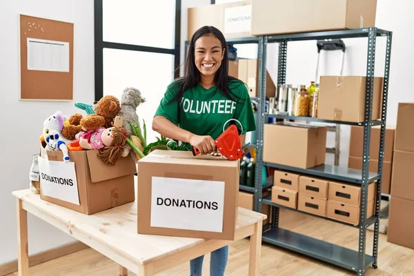 Gönüllü Üniformalı Genç Latin Kadın Yardım Merkezinde Bağış Kutusu Paketliyor — Stok fotoğraf