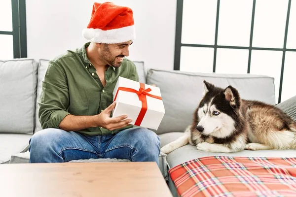 Jovem Hispânico Homem Segurando Presente Sentado Sofá Com Cão Por — Fotografia de Stock