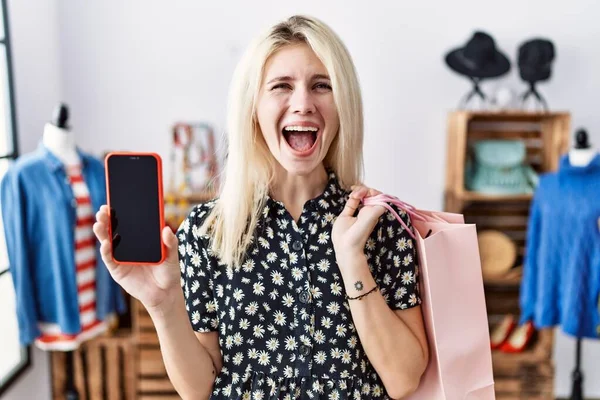 Mladá Blondýnka Drží Nákupní Tašky Ukazující Obrazovku Smartphone Slaví Šílený — Stock fotografie
