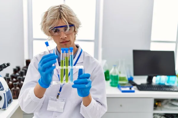 年轻的金发男子科学家在实验室拿着试管 — 图库照片