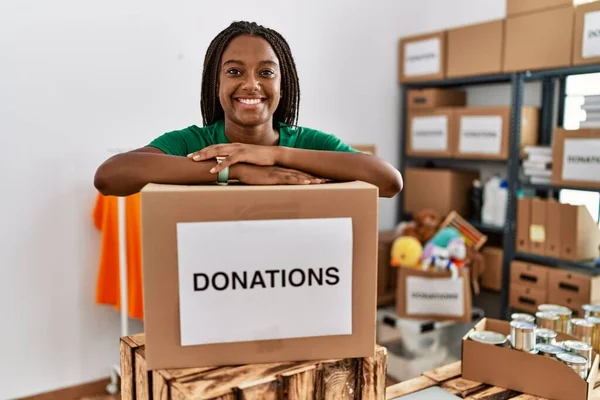 身穿志愿制服的年轻非洲裔美国妇女依靠慈善中心的捐赠一揽子计划 — 图库照片