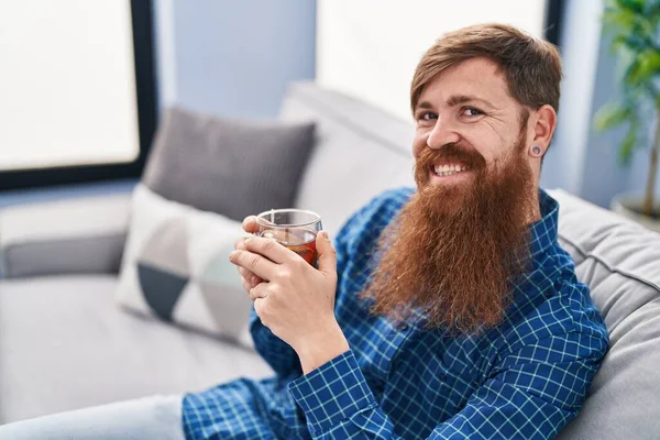 Giovane Uomo Rossa Che Beve Seduto Sul Divano Casa — Foto Stock