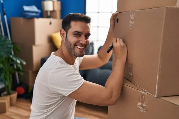 Joven Hispano Sonriendo Confiado Escribiendo Una Caja Cartón Nuevo Hogar —  Fotos de Stock