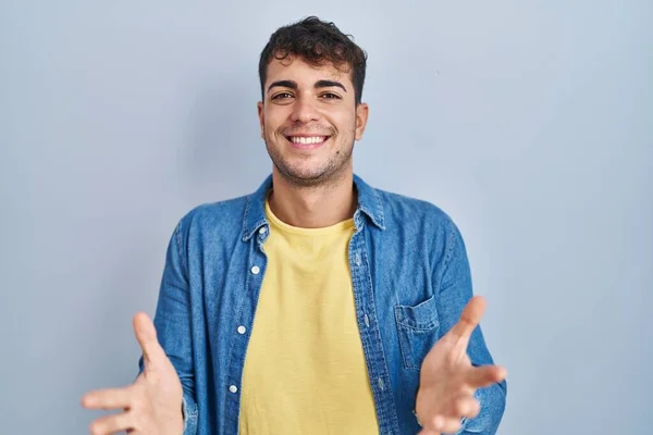 Jovem Hispânico Homem Sobre Fundo Azul Sorrindo Alegre Oferecendo Mãos — Fotografia de Stock