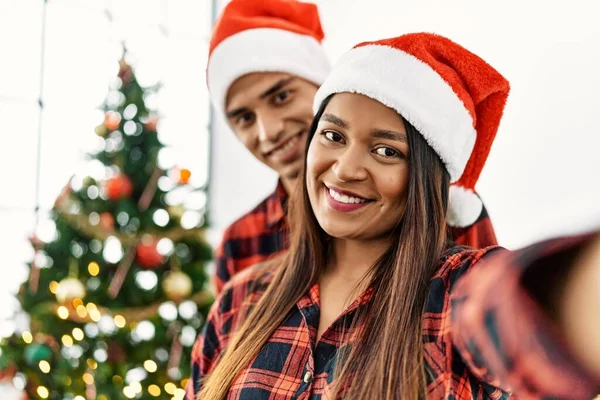 Young Latin Couple Wearing Christmas Hat Making Selfie Smartphone Home — 스톡 사진