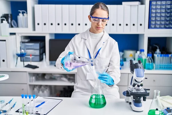 年轻女科学家在实验室测量液体 — 图库照片