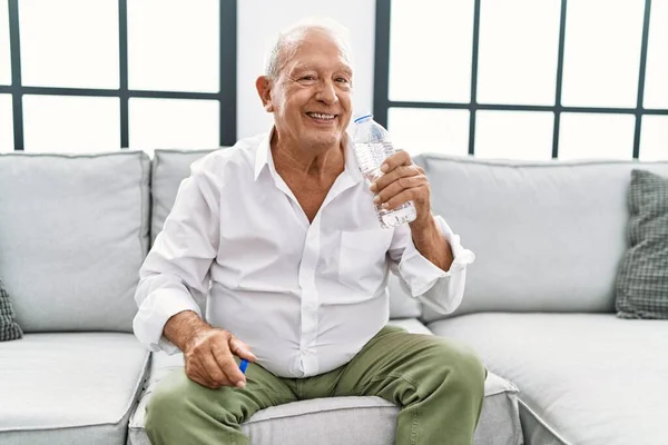 Senior Muž Pije Láhev Vody Sedí Pohovce Doma — Stock fotografie