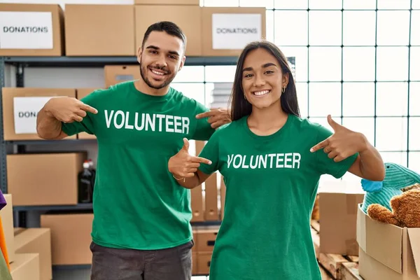 Joven Pareja Latina Sonriendo Feliz Señalando Uniforme Voluntario Centro Caridad — Foto de Stock