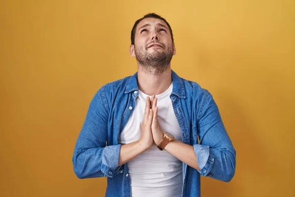 Uomo Ispanico Piedi Sfondo Giallo Implorando Pregando Con Mani Insieme — Foto Stock