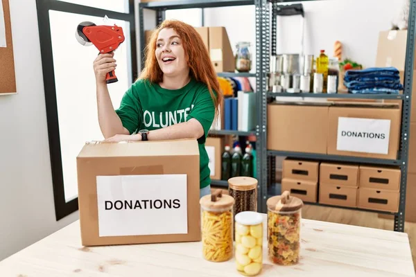 Mujer Pelirroja Joven Con Uniforme Voluntario Embalaje Caja Donaciones Centro — Foto de Stock