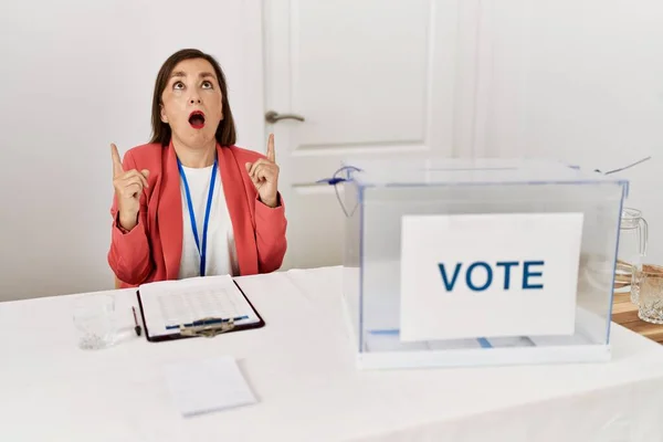 Piękna Latynoska Kobieta Średnim Wieku Wyborach Politycznych Siedząca Głosowaniu Zdumiona — Zdjęcie stockowe