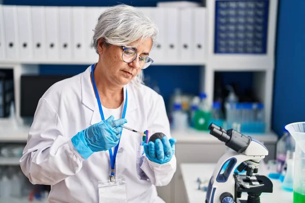 中年妇女穿着科学家制服在实验室分析鳄梨 — 图库照片