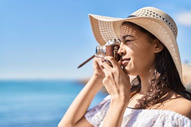 Genç Afro-Amerikan kadın turist deniz kenarında kamera kullanarak gülümsüyor.