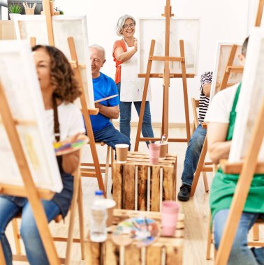 Resim stüdyosunda gülümseyen orta yaşlı öğrencilerden oluşan bir grup..