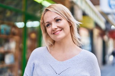 Young blonde woman smiling confident looking to the side at street