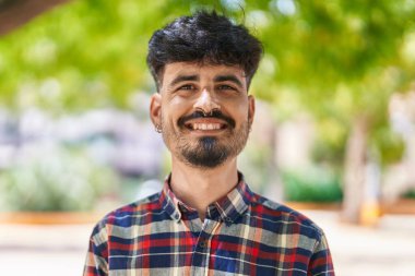 Parkta kendinden emin gülümseyen İspanyol genç adam.