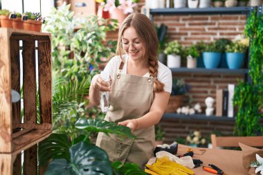 Çiçekçide su karıştırıcı kullanan genç sarışın kadın.