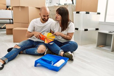 Genç İspanyol çift mutlu bir şekilde gülümsüyor. Yeni evinde boya rengi seçiyor..