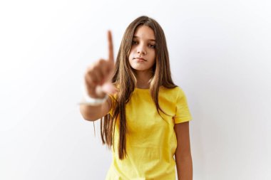 Genç esmer kız izole arka planda yan yana duruyor. Parmağını kaldırmış ve kızgın bir ifadeyle işaret ediyor. 