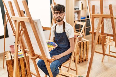 Sanat stüdyosunda sakallı bir İspanyol. Düşünce tarzı ve ayık yüz ifadesi. Kendine güveni tam görünüyor. 