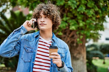 Genç İspanyol adam parkta telefonla konuşuyor.