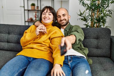 Genç İspanyol çift mutlu bir şekilde gülümsüyor. Evdeki kanepede oturup film izliyorlar..