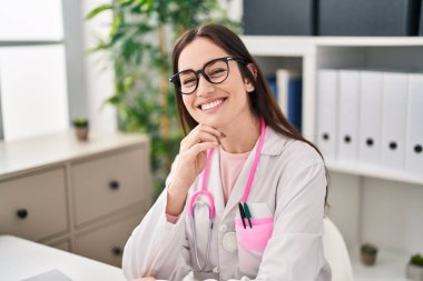 Klinikte çalışan doktor üniforması giyen genç bir kadın.