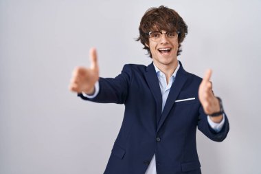 İspanyol iş adamı gözlüklü genç adam kameraya bakıyor sarılmak için kollarını açmış gülümsüyor. Mutluluğu kucaklayan neşeli bir ifade.. 