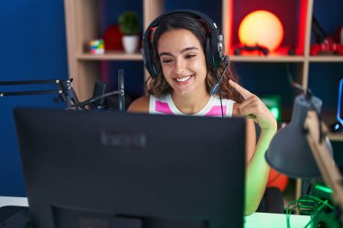 Video oyunları oynayan genç İspanyol kadın mutlu bir şekilde elini ve parmağını işaret ediyor. 