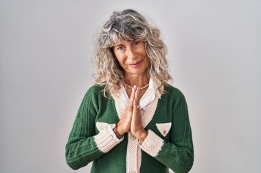 Orta yaşlı bir kadın beyaz arka planda duruyor. Birlikte dua ediyoruz. Affedilmek için dua ediyoruz.. 