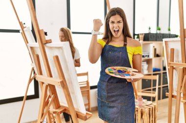 Sanat sınıfındaki genç İspanyol kadın sinirlenmiş ve sinirlenmiş öfkeyle bağırıyor, öfkeyle bağırıyor ve el kaldırıyor. 