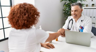 Doktor üniforması giyen orta yaşlı bir adam ve kadın klinikte tıbbi danışmanlık yapıyorlar.