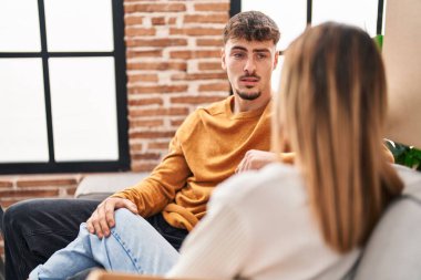 Genç adam ve kadın çift yeni evlerinde kanepede oturmuş sohbet ediyorlar.