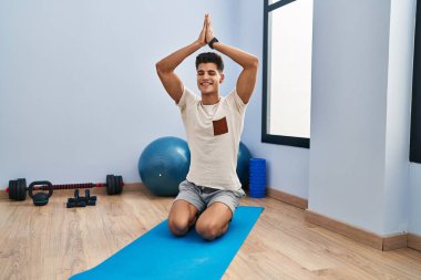 Spor merkezinde yoga eğitimi alırken gülümseyen İspanyol genç adam.