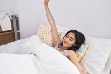 Genç İspanyol kız gülümseyerek yatak odasında kendine güvenerek uyanıyor.