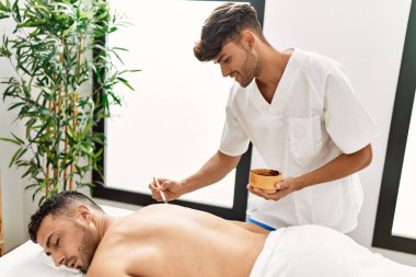 İki İspanyol erkek fizyoterapist ve hasta güzellik merkezinde cilt bakımı yaptırıyor.