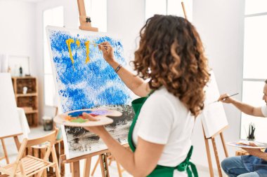 Resim stüdyosunda arka planda resim yapan iki orta yaşlı öğrenci..