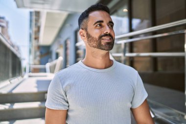 Güneşli bir günde mutlu bir şekilde gülümseyen sakallı İspanyol genç adam.