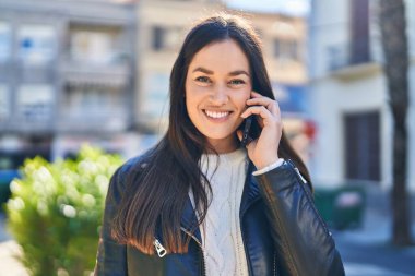 Parktaki akıllı telefondan konuşan, kendine güvenen genç bir kadın.