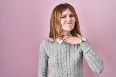 Güzel bir kadın pembe arka planda duruyor. Bıçak gibi elleriyle boğazını kesiyor. Saldırganlığı şiddetle tehdit ediyor. 