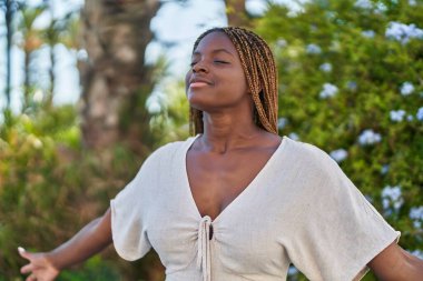 Parkta gözleri kapalı nefes alan Afrikalı Amerikalı kadın.